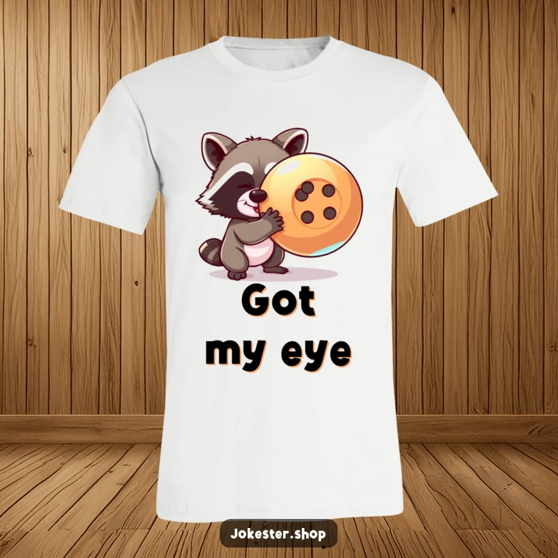 Funny raccoon t-shirt showing a mischievous raccoon trying to steal a giant, shiny button, perfect for expressing playful intent.